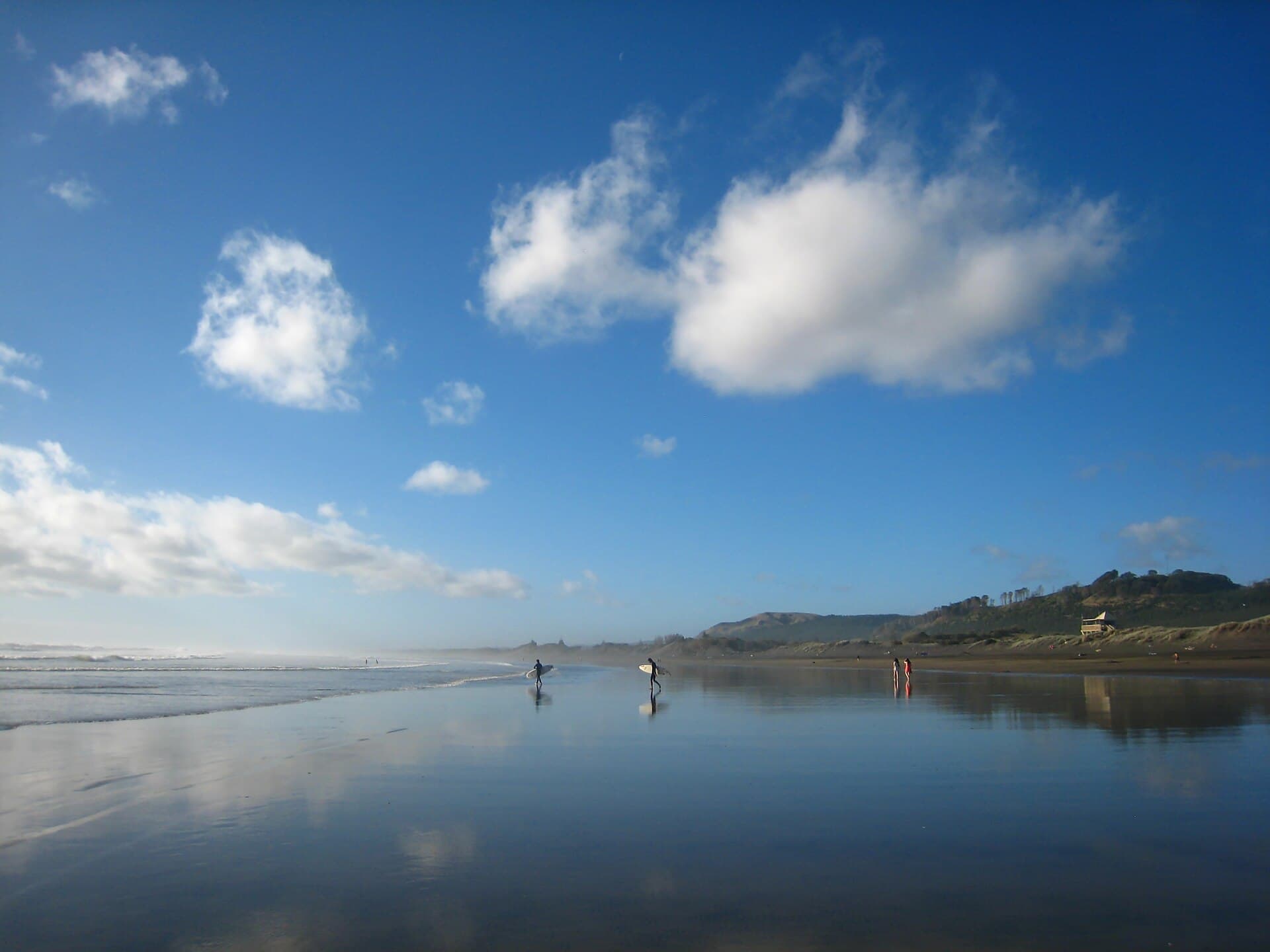Reflections on the wet black sand at Muriwai Beach